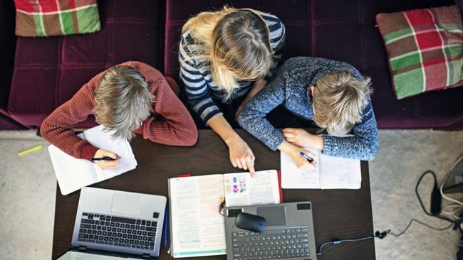 Mother helping sons with homeschooling at home during Covid lockdown.