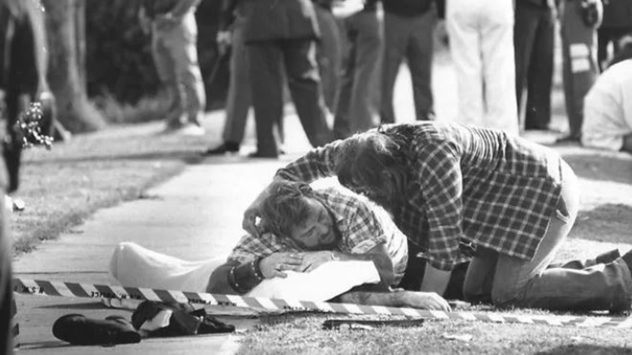 A man is comforted by a friend as he mourns the loss of a friend at the Milperra bikie massacre.