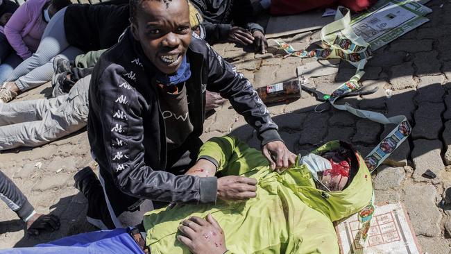 A suspected looter pleads for help after his brother was struck by a rubber bullet in Soweto. Picture: AFP