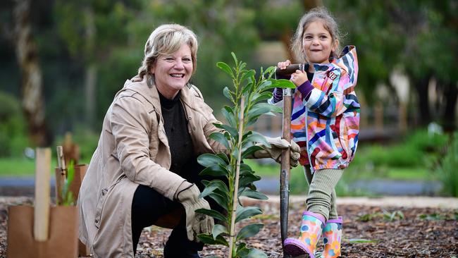 Dr Sheryn Pitman and her granddaughter Mahi, 3, help garden staff plant a golden wattle (Acacia pycnantha) near the children's play area at Wittunga Botanic Garden. Picture: Mark Brake