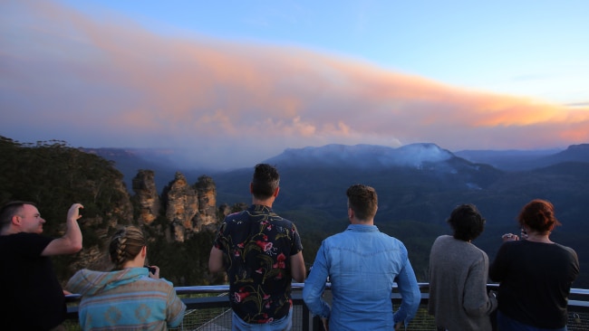 People watch smoke from the Three Sisters rock formation in Katoomba, New South Wales. Picture: AAP Image/Steven Saphore