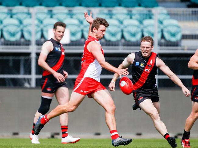 Clarence's Jarrod Harper kicks forward at North Launceston's Mark Walsh closes in. Picture: PATRICK GEE