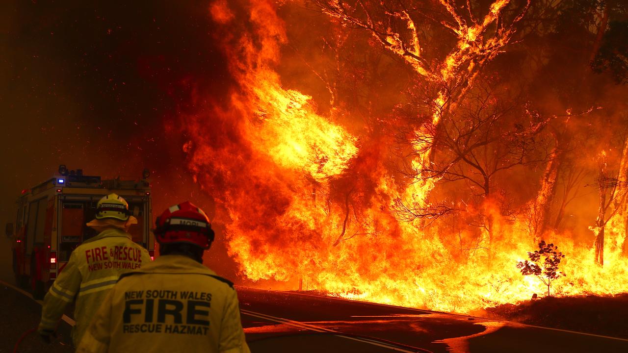 Fire and Rescue members run to move their truck as a bushfire burns next to a major road and homes on the outskirts of the town of Bilpin. Picture: Getty