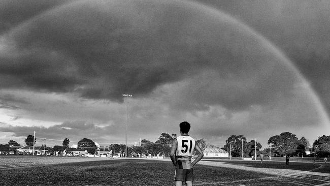 A rainbow lines the sky over a suburban ground.