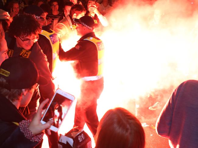 Police move in as flares are set off on Swan Street, Richmond as Tigers fans celebrate their team's victory in the 2019 AFL Grand Final in Melbourne, Saturday, September 28, 2019. Richmond have beaten GWS by 89 points in the AFL grand final at the MCG. (AAP Image/David Crosling) NO ARCHIVING