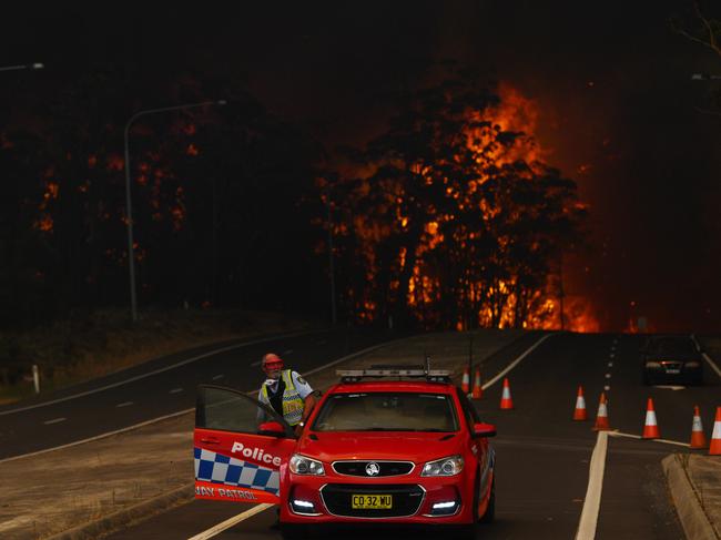 A police officer prepares to flee his roadblock on the Princes Highway near the town of Sussex Inlet on December 31. Picture: Sam Mooy/Getty Images