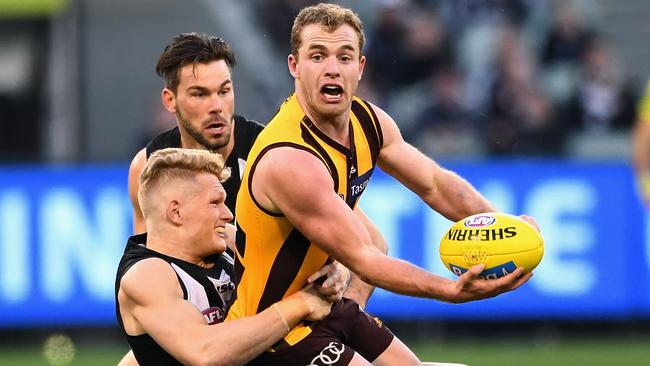 Tom Mitchell gets a handball away while being tackled by Adam Treloar.