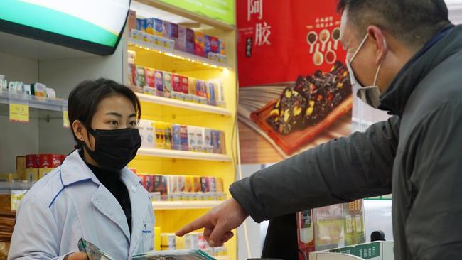 A pharmacy worker sells face masks in Wuhan, China, on Wednesday. Picture: AP