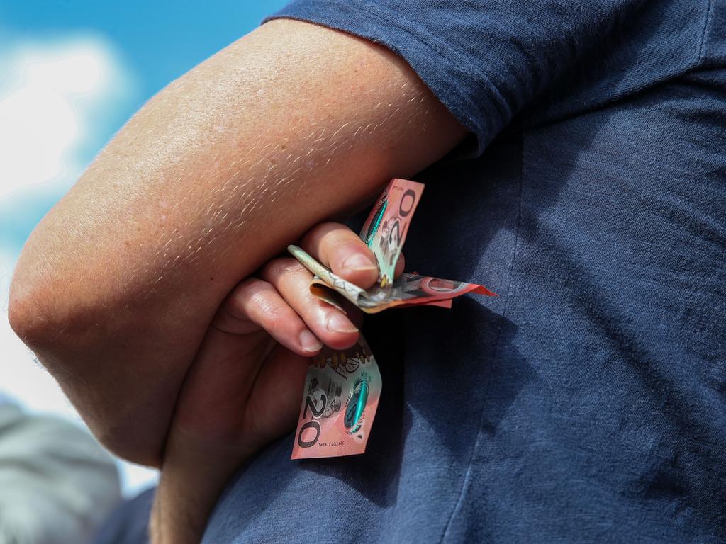 One man holds onto a handful of notes during a game of Two-Up. (Photo by Roni Bintang/Getty Images)