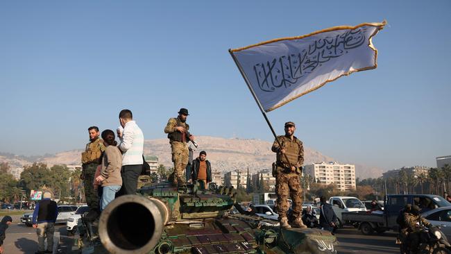 An anti-government fighter waves an Islamic flag from atop a tank in Damascus on December 9. Picture: AFP