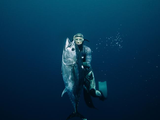 Sam Lennox catching dinner from the depths of Pedra Branca. The image features in Marti Paradisis’s new book. Picture: Adam Gibson