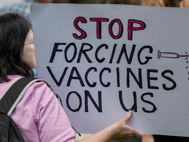 A protestor holding a placard is seen during the 'Wake Up Australia!' march against mandatory vaccinations at Hyde Park in Sydney, Saturday, May 30, 2020. (AAP Image/Bianca De Marchi) NO ARCHIVING