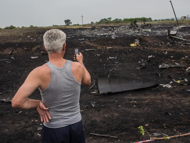An onlooker uses his phone to photograph the scene of the Air Malaysia plane crash. Picture: Brendan Hoffman