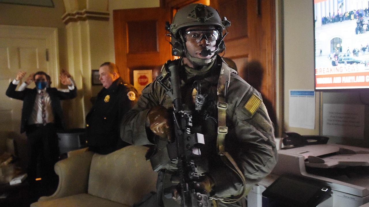 Congress staffers hold their hands up while Capitol Police Swat teams check everyone in the room as they secure the floor of Trump suporters in Washington, DC on January 6, 2021. Picture: Olivier DOULIERY / AFP.