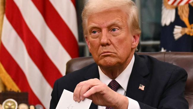 US President Donald Trump holds up outgoing President Joe Biden's letter as he signs executive orders in the Oval Office of the WHite House in Washington, DC, on January 20, 2025. (Photo by Jim WATSON / POOL / AFP) / ALTERNATE CROP