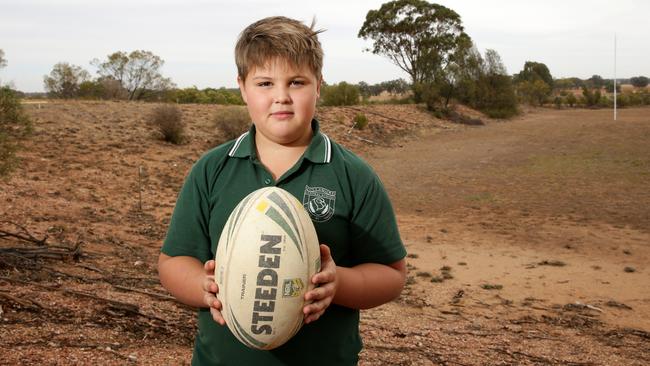 Tullamore student Archie Aveyard, 9, who loves his footy is pictured at the school oval which will no longer be watered from Friday. Picture: Jonathan Ng