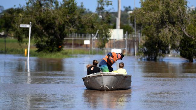 A family uses a boat to get to their house through floodwaters in Rockhampton on Tuesday. Picture: AAP Image/Dan Peled