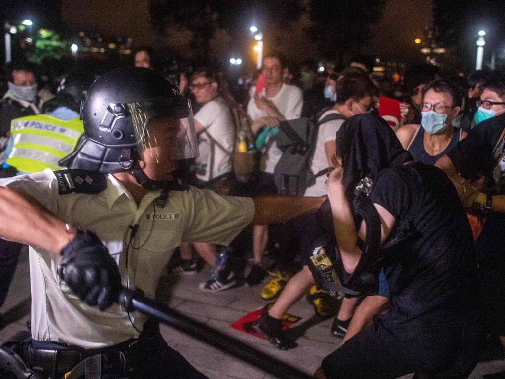 An officer swings his baton as police sprayed tear gas after protesters broke through barriers in after clashes outside the Legislative Council. Picture: Philip Fong / AFP