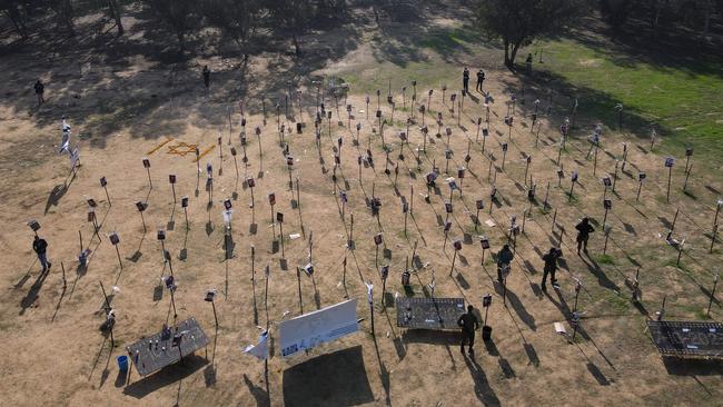 Israeli soldiers walk among the pictures of people taken captive or killed by Hamas militants duing the Supernova music festival on October 7.