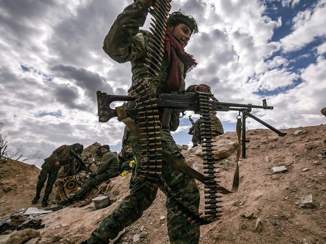 TOPSHOT - A fighter of the Syrian Democratic Forces (SDF) walks carrying a machine gun at a position close to the camp of Baghouz where remaining Islamic State (IS) group fighters and their families are holding out in the last position controlled by IS, awaiting to advance on them in the countryside of the eastern Syrian province of Deir Ezzor on March 17, 2019. (Photo by Delil SOULEIMAN / AFP)