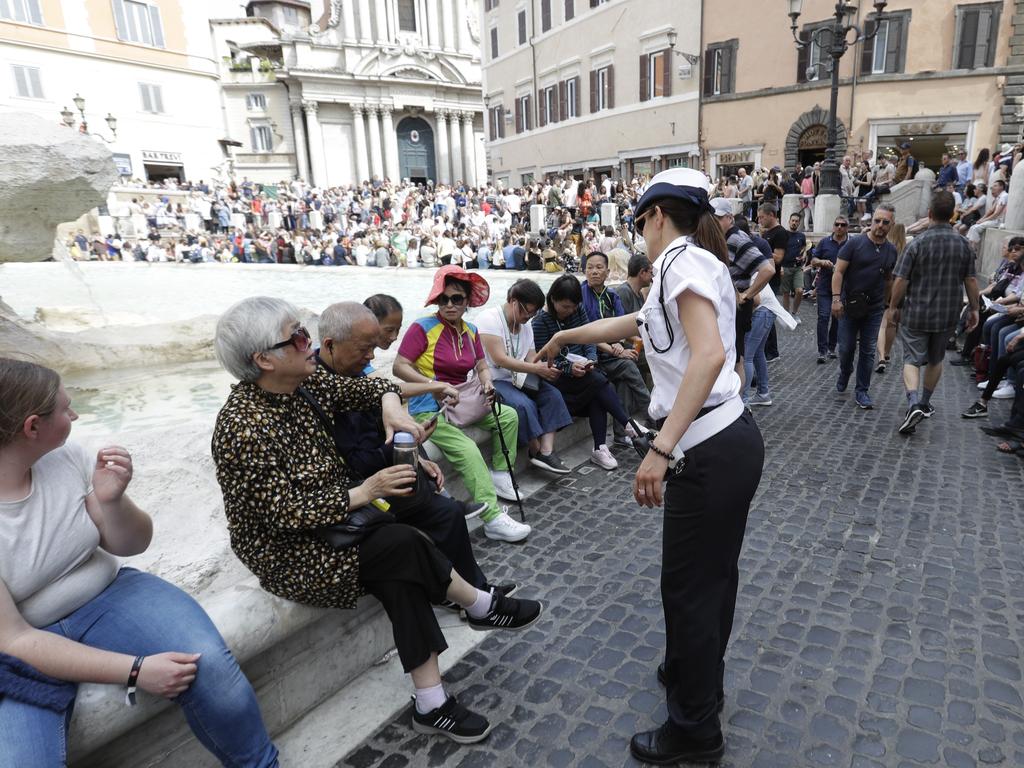 A city police officer talks to tourists gathered in front of Trevi fountain. Picture: AP/Gregorio Borgia