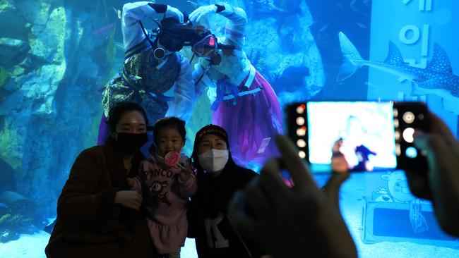 Visitors pose for photographs with divers at an event to celebrate New Year at an aquarium in Seoul, South Korea. Picture: Getty Images