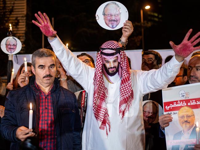 A protester wears a mask of depicting Saudi Crown Prince Mohammad Bin Salman with red painted hands next to people holding posters of Saudi journalist Jamal Khashoggi during the demonstration outside the Saudi Arabia consulate in Istanbul. Picture: AFP