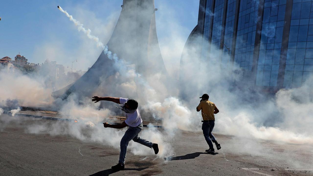 Palestinian demonstrators throw teargas canisters back at Israeli forces during clashes near the Jewish settlement of Beit El near Ramallah. Picture: ABBAS MOMANI / AFP