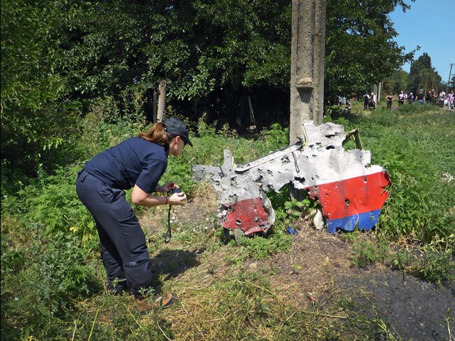 An Australian Federal Police agent examines a piece of debris after the downing of Flight MH17.