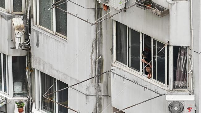 A woman looks out the window of a residential building during a Covid-19 lockdown in the Jing'an district in Shanghai. Picture: AFP