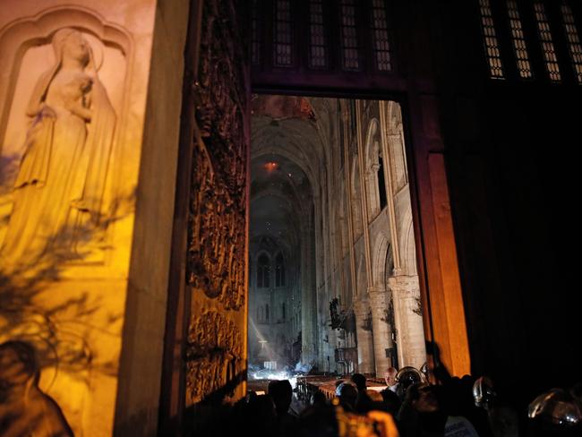 This general view from the entrance shows smoke rising in front of the altar cross at Notre-Dame Cathedral in Paris on April 15, 2019, after a fire engulfed the building. (Photo by PHILIPPE WOJAZER / POOL / AFP)