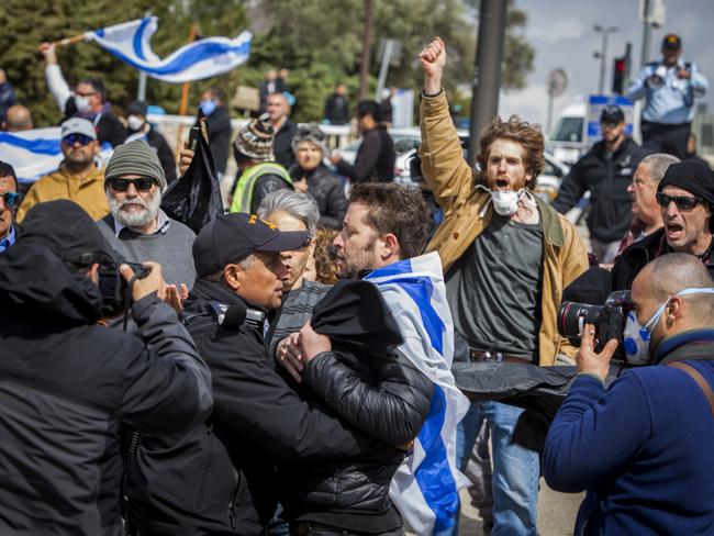 Israeli police officers scuffle with a man during a protest outside the Israeli parliament in Jerusalem, Thursday, March 19, 2020. Hundreds of people defied restrictions on large gatherings to protest outside parliament Thursday, while scores of others were blocked by police from reaching the area as they accused Prime Minister Benjamin Netanyahu's government of exploiting the coronavirus crisis to solidify his power and undermine Israel's democratic foundations. (AP Photo/Eyal Warshavsky)