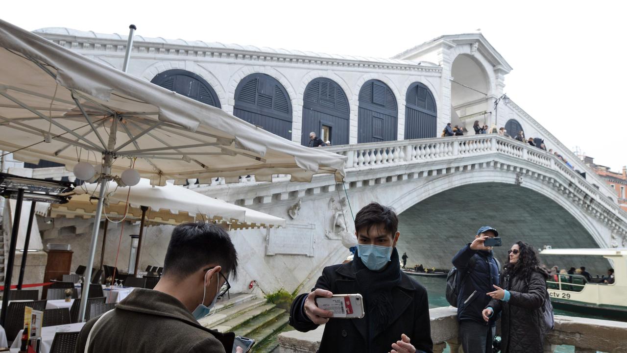 Tourists pose for selfies in front of the Rialto Bridge in Venice after the carnival was cancelled due to a surge in coronavirus cases in Italy. Picture: AFP/ANDREA PATTARO