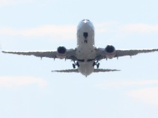 Workers cutting concrete on the runway with aircraft taking off over them, Brisbane Airport. Picture: Liam Kidston