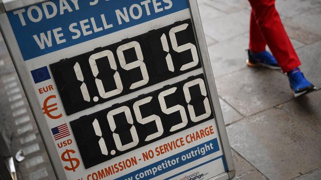 Pedestrians walk past a board displaying the price of Euro and US dollars against British pound Sterling. Picture: AFP