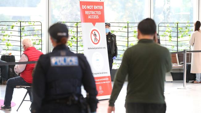 Police escort Passengers to a holding area after arriving from NSW at the Adelaide Airport when SA’s borders were closed during the Covid pandemic. Picture: NCA NewsWire / Kelly Barnes