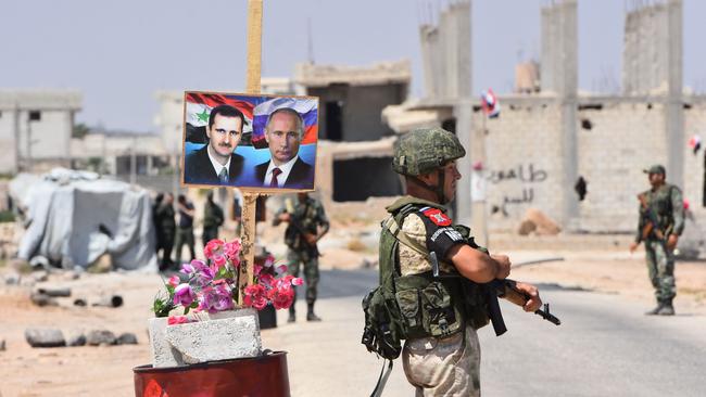 Russian and Syrian forces stand guard near posters of President Bashar al-Assad and his Russian counterpart Vladimir Putin at the Abu Duhur crossing in Syria in 2018. Picture: AFP