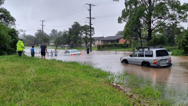 A four-wheel drive tows a sedan which became stranded in floodwater on Bray Street, Coffs Harbour last February. Picture: Steve Zaal