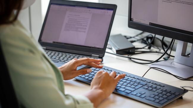 Close-up of woman typing on computer keyboard at workplace. Businesswoman using desktop computer in office.