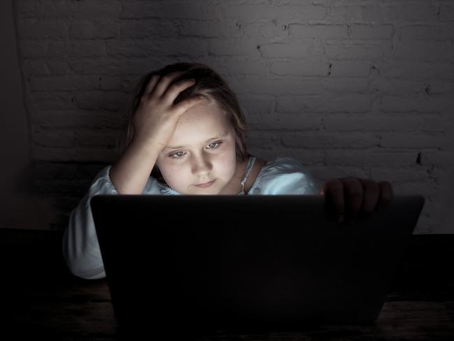 Scared sad girl bullied online on laptop suffering cyber bullying harassment. School girl humiliated on the internet by classmates feeling desperate and intimidated. Children victim of bullying.