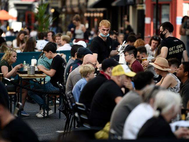 Customers eat at tables outside restaurants in Soho, in London as the UK has lifted its quarantine rules for vaccinated travellers from the EU and US. Picture: AFP