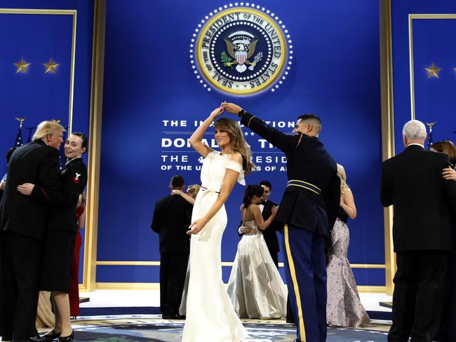 President Donald Trump, left, dances with Navy Petty Officer 2nd Class Catherine Cartmell as first lady Melania Trump is spun by Army Staff Sgt. Jose A. Medina during a dance at their third and final ball.