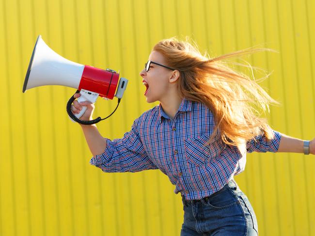 Young attractive girl activist in shirt yelling into loudspeaker. A single picket. Active life position. The struggle for women's rights