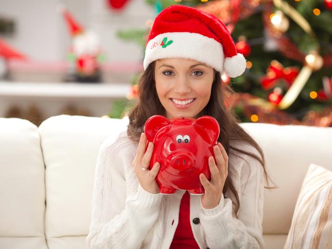 "Smiling woman wearing santa hat sitting on sofa and holding piggy bank, with christmas decoration around. Saving for christmas concept.Please, see CHRISTMAS images with this FAMILY, for lightbox click the image below."