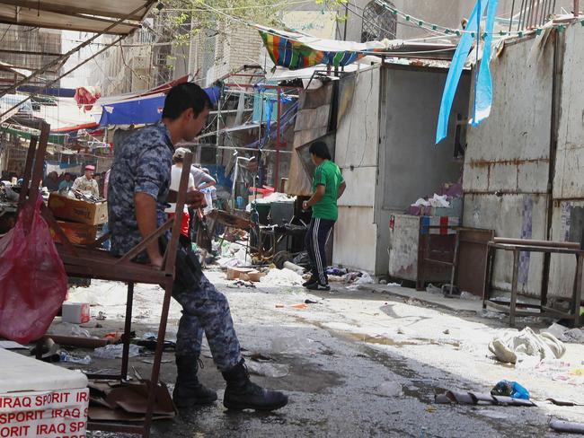 An Iraqi policeman and civilians inspect the site of a bomb attack in Shorja Market in Baghdad, Iraq, on July 17. AP Photo/Hadi Mizban