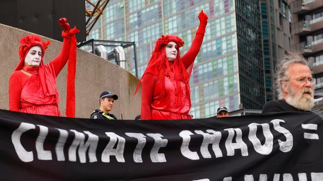 An Extinction Rebellion protester scales the Victorian Arts Centre in Melbourne to protest on climate change as other protesters gather at the base. Picture: Ian Currie