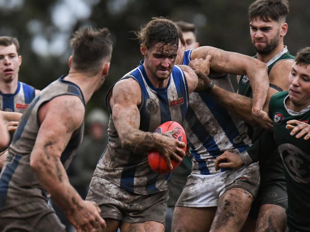 A Macleod player emerges from a pack covered in mud. Pictures: Nathan McNeill.