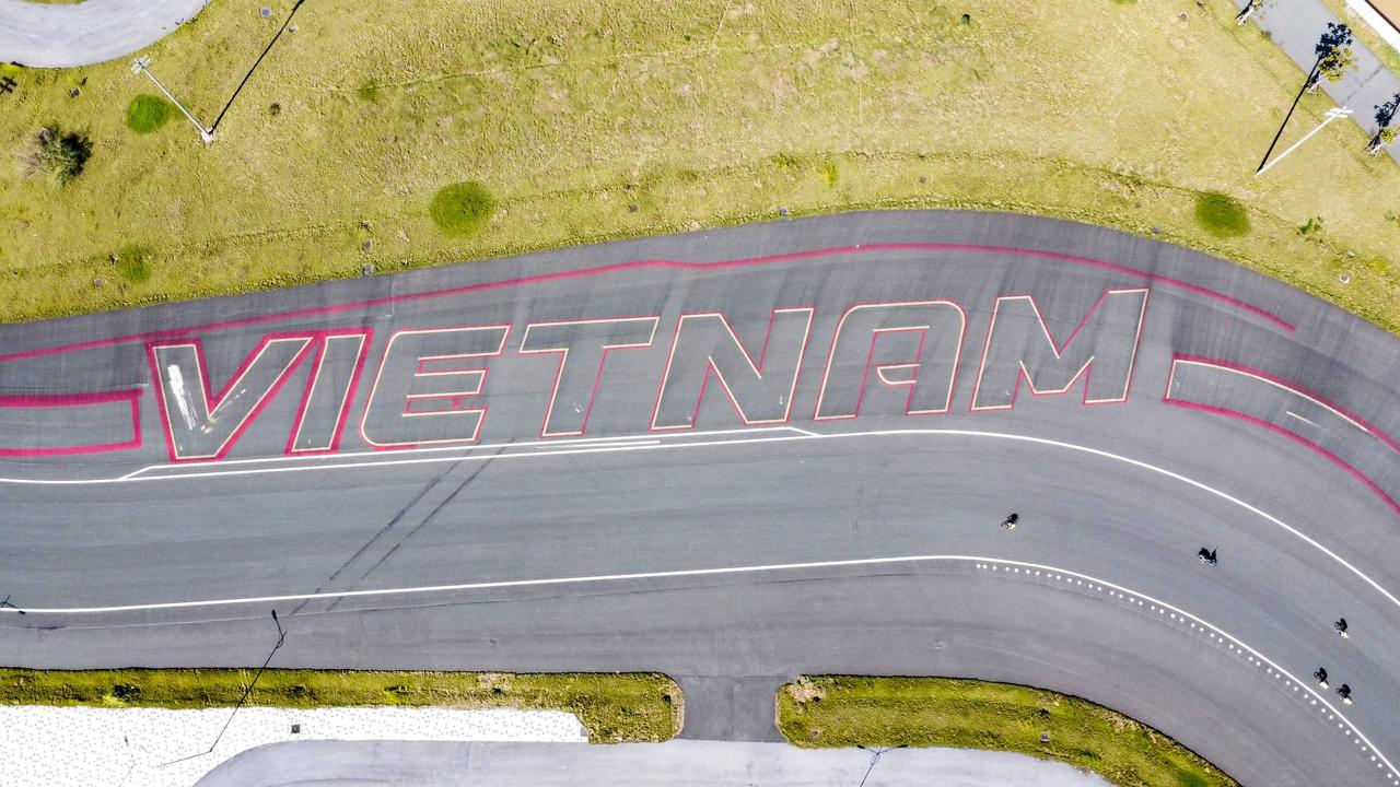 Foto udara yang diambil pada 11 Oktober 2022 ini menunjukkan pengendara sepeda melewati prasasti "Vietnam" di trek Formula Satu yang ditinggalkan di Hanoi.  (Foto oleh Nhac NGUYEN / AFP)