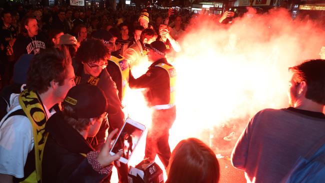 Police move in as flares were set off on Swan Street. Picture: AAP Image/David Crosling