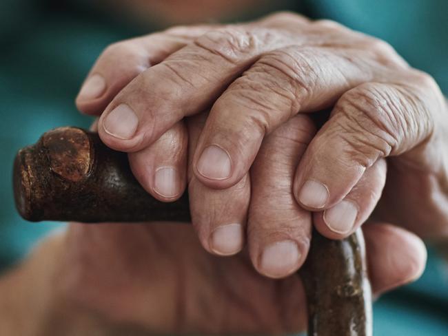 Cropped shot of an unrecognizable man leaning on his walking stick